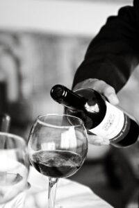 A classic black and white photograph of a wine being poured into a glass, capturing elegance in an Italian setting.
