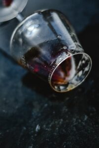 A detailed shot of a tipped glass with remnants of liquid on a textured dark background.